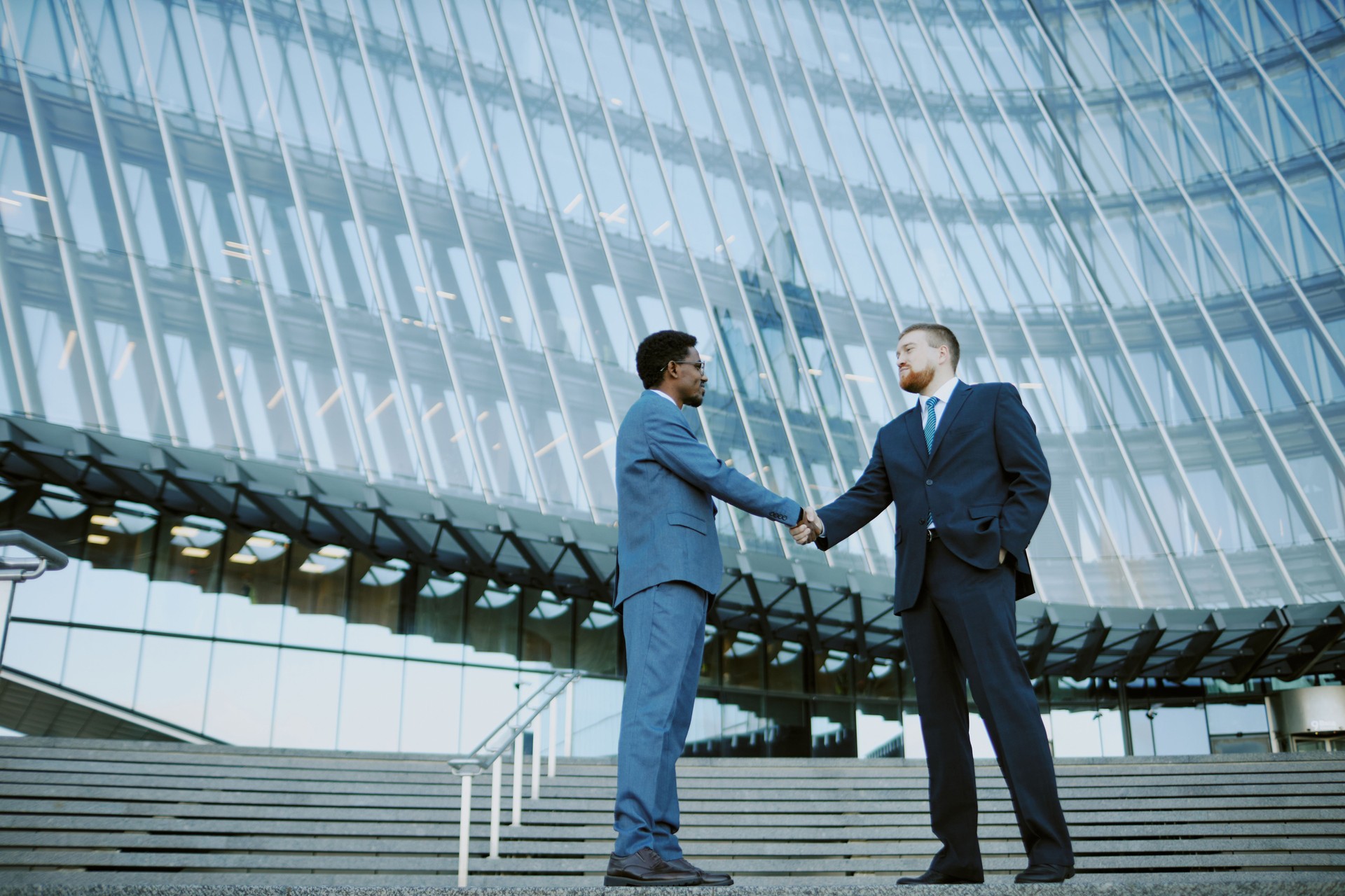 Two Businessmen Shaking Hands Outside Modern Office Building